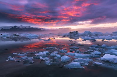 A beautiful sunset at Jökulsárlón glacier lagoon lights up the sky with vibrant shades of pink.