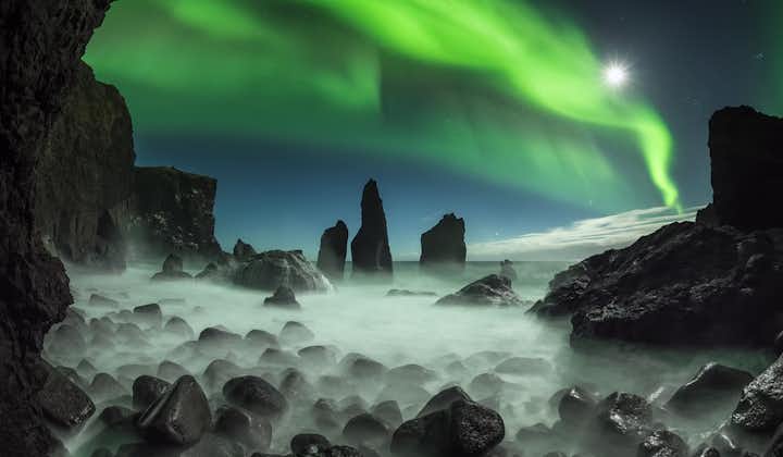 Nordlichter tanzen über dunklen Felsformationen auf der Halbinsel Reykjanes.
