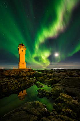 แสงออโรร่าเต้นรำอยู่เหนือหนึ่งในประภาคารของประเทศไอซ์แลนด์.