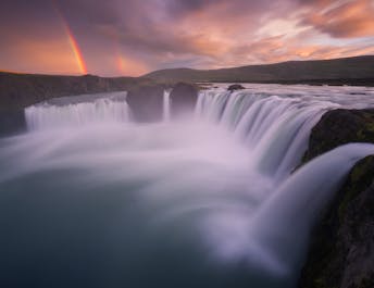 The mighty and beautiful waterfall Goðafoss thunders into the Skjálfandafljót river accompanied by a gorgeous rainbow.