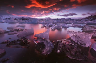 Icebergs glisten and reflect the warm colours of a sunset at Jökulsárlón glacier lagoon in the southeast of Iceland.