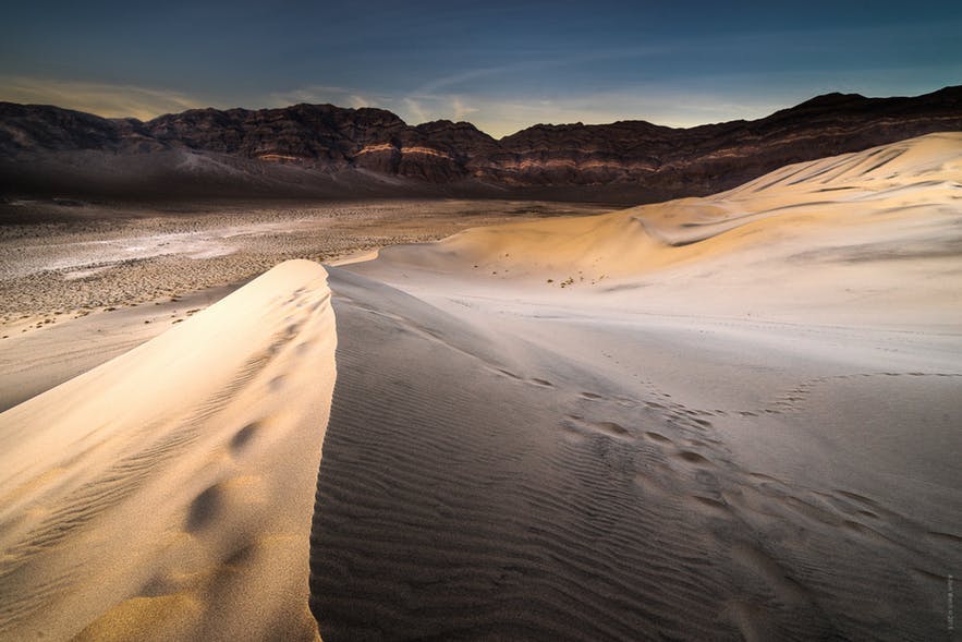 Dunes sit in the foreground as mountains sit in the background - landscape Photography | Everything You Need To Know
