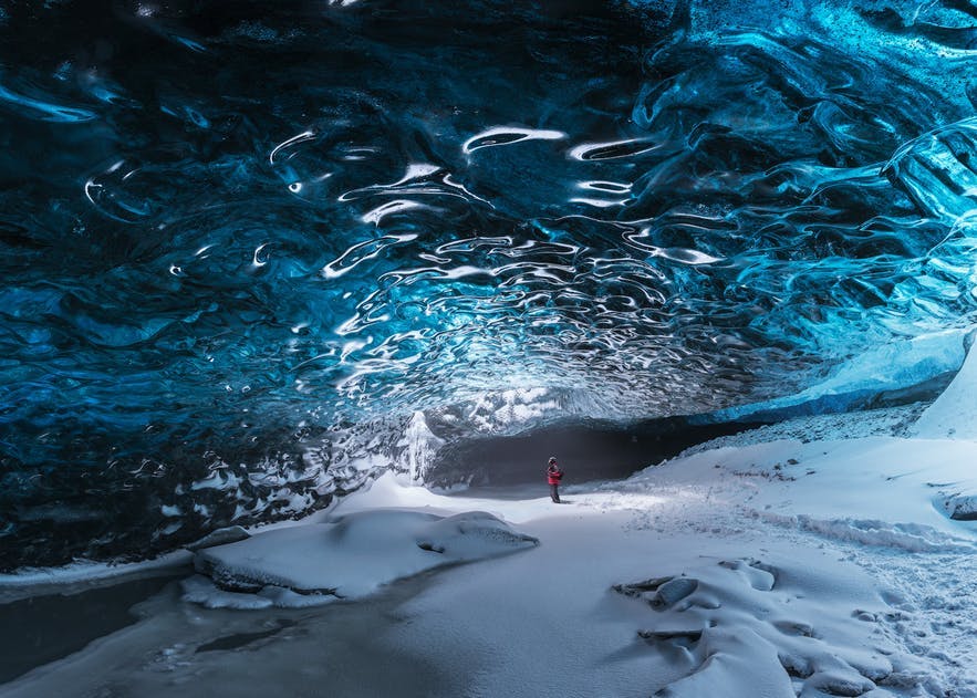 A person stands under a glacier in Iceland - landscape Photography | Everything You Need To Know