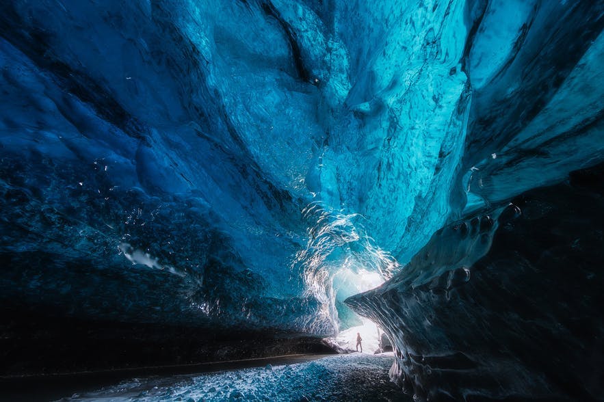The scale of an ice cave is shown by including a visitor at the end of the tunnel - landscape Photography | Everything You Need To Know