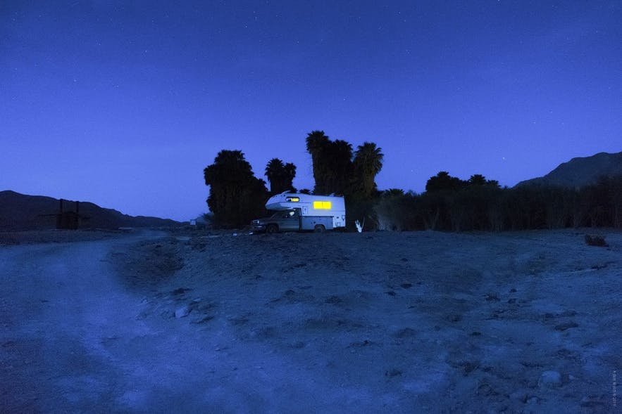 A campervan sits in a field as the blue hour hits, causing a blue hue to fall over the scene - landscape Photography | Everything You Need To Know