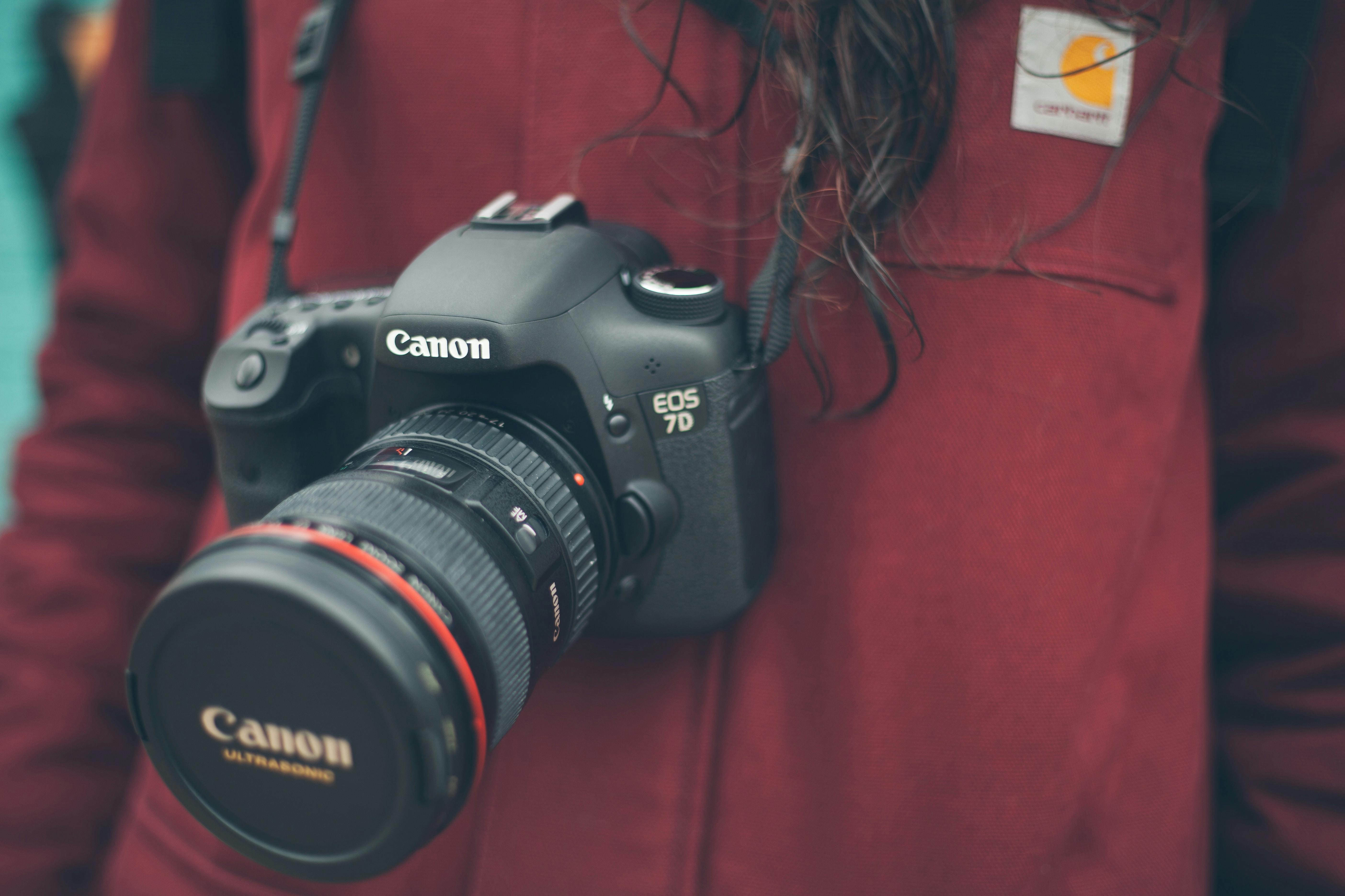 egy digitális fényképezőgép lóg a nyak körül egy személy egy piros jumper a háttérben - típusú kamerák | digitális