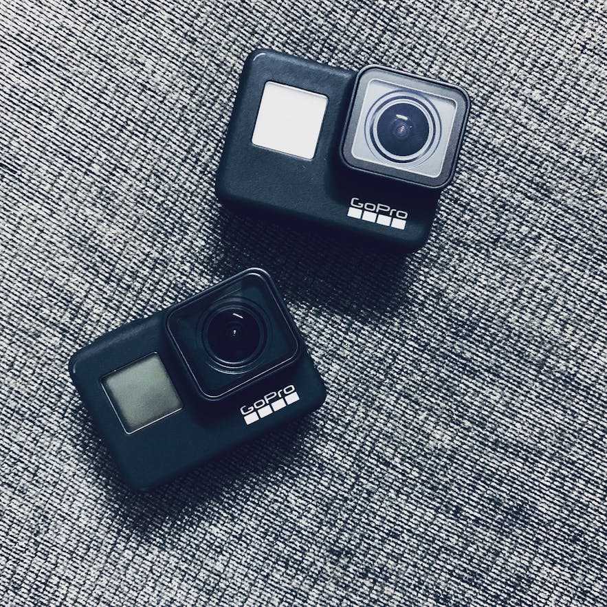 Two Black GoPro adventure cameras lie on  grey fabric surface - types of cameras | digital