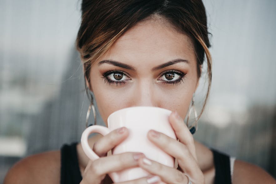 A woman drinking from a coffee cup.