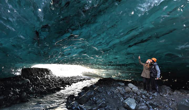 Two adventurers are captivated by the beauty of the blue ice cave.