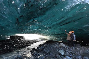Two adventurers are captivated by the beauty of the blue ice cave.
