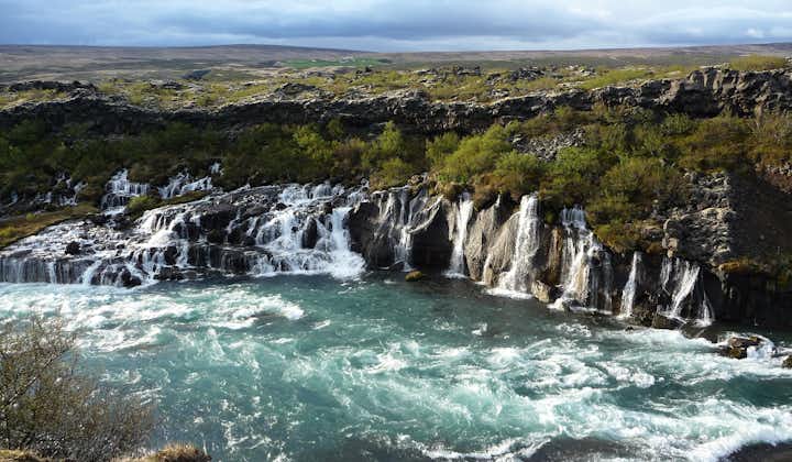 The natural beauty of Hraunfossar leaves visitors in awe as the water gracefully flows through the rugged landscape.