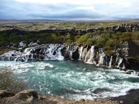 The natural beauty of Hraunfossar leaves visitors in awe as the water gracefully flows through the rugged landscape.