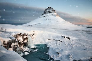 Kirkjufell mountain stands tall and majestic in a serene winter wonderland.