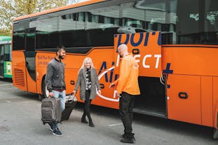 A bus staff assists travelers in loading their luggage for this bus transfer to Keflavik Airport.