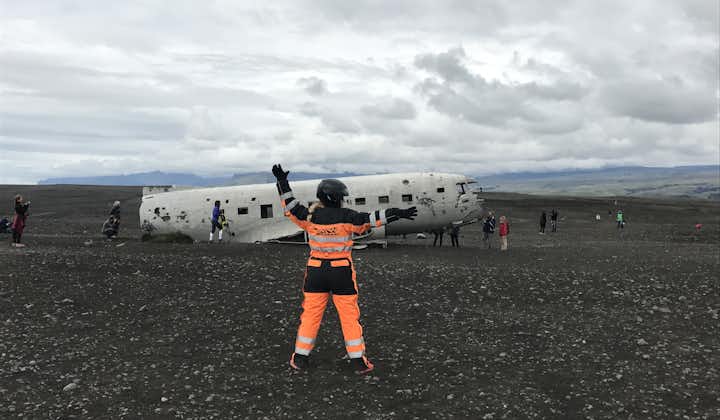 A person in an orange suit pretending to direct air traffic at the DC-3 plane wreck at Solheimasandur beach.