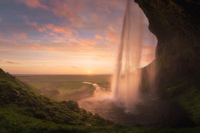 Seljalandsfoss waterfall tumbles in front of a cavern, overlooking the ocean.