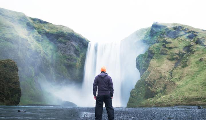 A traveler posing in front of the beautiful Skogafoss waterfall in the South Coast of Iceland.