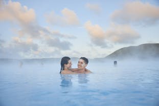 A couple with silica mud masks on their faces, relax in the milky-blue waters of the Blue Lagoon geothermal spa.
