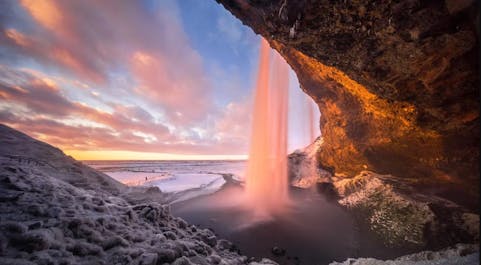 Seljalandsfoss Waterfall invites you to witness its captivating 60-meter drop and experience the unique thrill of walking behind the cascading curtain of water.