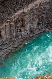 Studlagil Canyon: A geological masterpiece carved through time, revealing striking basalt columns framed by the vibrant beauty of Icelandic nature.