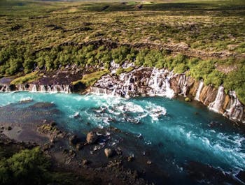 Hraunfossar reveals a mesmerizing display of countless waterfalls emerging from beneath ancient lava fields in Iceland.
