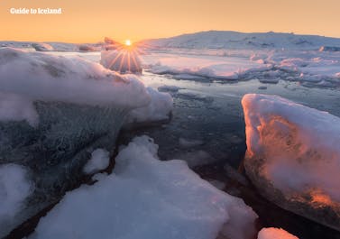 The white floating icebergs at Jokulsarlon glacier lagoon contrast perfectly against the orange sky and setting sun.