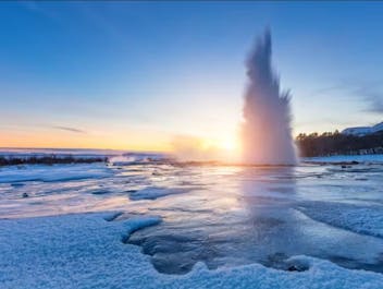 Strokkur geyser erupts in a stunning display of icy beauty during a winter morning.