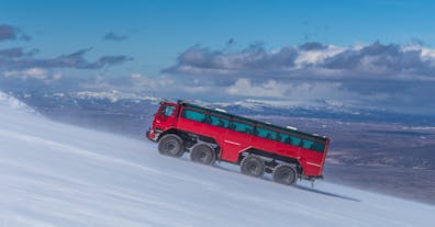A red monster truck drives up the Langjokull glacier.